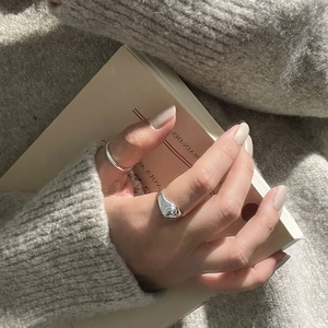 Primo piano di anelli d'argento minimalisti indossati sulla mano su maglione lavorato