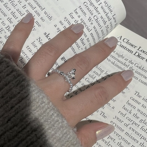 Detail of beaded S925 sterling silver ring with floral cross charm on finger