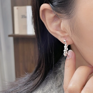 Detail view of 925 sterling silver beaded tassel earrings worn by a model in soft lighting