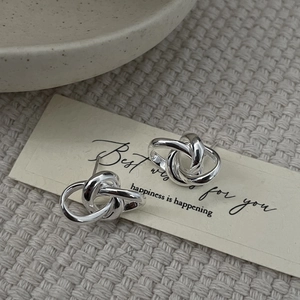 Detailed view of silver minimalist interwoven knot stud earrings on a card