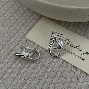 Detailed macro view of S925 sterling silver knot earrings with visible hallmark stamp