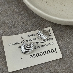 Vue détaillée de boucles d'oreilles conque en argent avec texture spirale ondulée