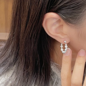Macro detail of 925 sterling silver beaded hoop earrings worn on earlobe for minimalist style