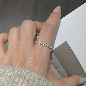 Close-up of S925 sterling silver beaded ring with heart and shell charms on hand