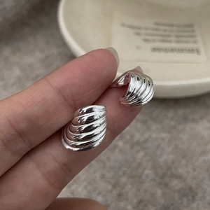 Détail macro des puces d'oreilles conque en argent sterling S925 à fini brillant