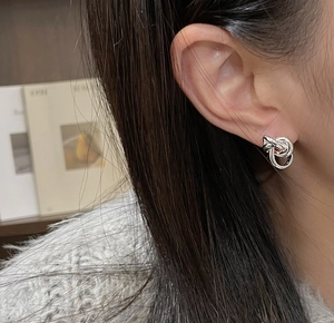 Close-up of S925 sterling silver intertwined knot stud earrings on female model