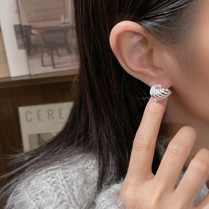 Gros plan sur l'oreille avec boucle d'oreille en argent massif en forme de coquillage