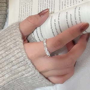 Minimalist S925 sterling silver woven twist ring worn on finger with aesthetic book background