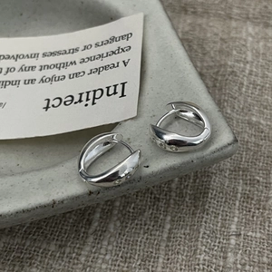 Polished S925 silver U-shaped earrings with inlaid zircons on a rustic ceramic edge