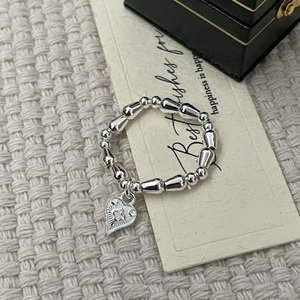 Detail view of silver beaded elastic bracelet with heart pendant on a gift card