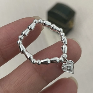 Detailed shot of elastic silver beaded ring featuring a heart pendant and star engraving
