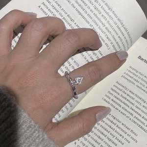 Detailed view of silver beaded ring with engraved heart pendant on model's hand