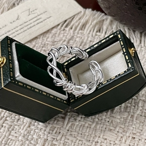 Detailed view of S925 sterling silver multilayer intertwined ring in green jewelry box