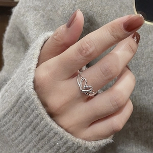 Detail of S925 sterling silver hollow heart ring worn on a finger with knit sweater background