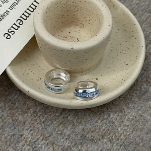 Macro detail of S925 sterling silver hoop earrings with rectangular blue zircon stones