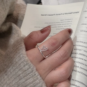 Detail of S925 sterling silver hollow heart ring worn on finger with a cozy lifestyle vibe