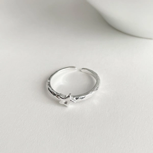 Macro detail of 925 silver adjustable ring showing star charm and hammered texture surface