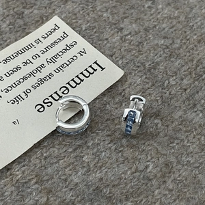 Classic silver hoop earrings with square light blue zircon stones on knitted fabric
