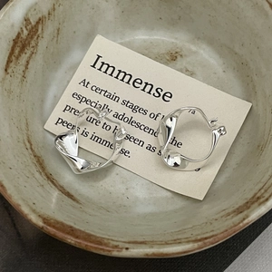 Macro shot of minimalist twisted S925 sterling silver earrings inside a vintage ceramic bowl