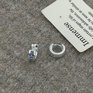 Detailed macro view of silver hoop earrings with inlaid square blue cubic zirconia stones
