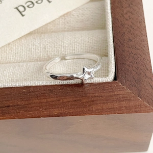 Macro detail of silver S925 star ring with hammered texture on wooden jewelry box