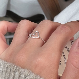 Close-up of 925 sterling silver heart chain ring on finger with soft knit sleeve backdrop