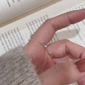 Detail shot of a minimalist S925 sterling silver chain ring with hanging beads on fingers