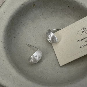 Close-up of brushed S925 sterling silver stud earrings with engraved star patterns