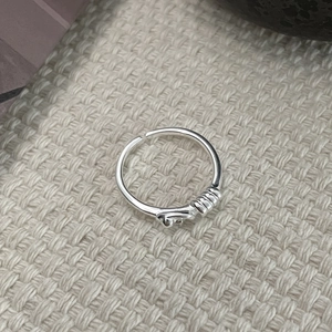 Gros plan détaillé de la bague nouée en argent sterling S925 sur un tissu texturé