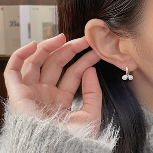 Gros plan de boucles d'oreilles cerises en argent S925 avec perles blanches sur un mannequin