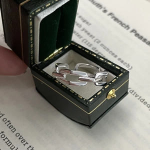 Close-up of silver chain link ring in vintage velvet box over an old book