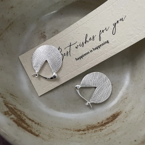Close-up of S925 sterling silver earrings showing brushed texture and hallmark stamp