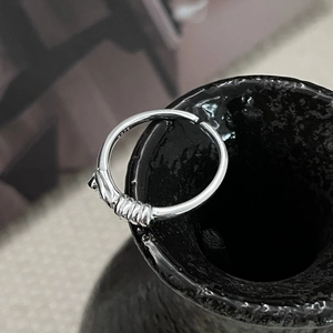 Gros plan d'une bague nouée en argent S925 avec texture filetée et poinçon de métal