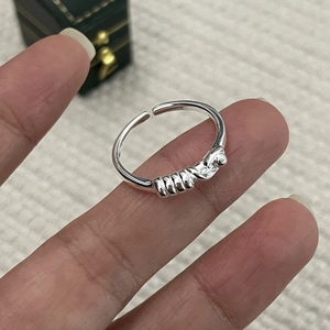Gros plan d'une bague nœud en argent sur un doigt avec finition métal poli