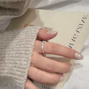 Gros plan d'une bague nœud en argent S925 sur doigt féminin dans une ambiance cosy