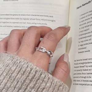 Detail of S925 sterling silver quilted buckle ring on finger with aesthetic book background