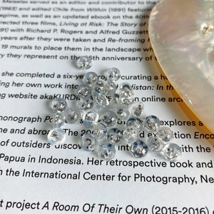 Transparent silicone earring backs on a magazine page with a decorative pearl shell
