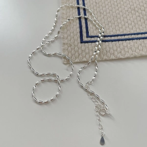 Macro detail of silver rice bead necklace with adjustable chain and teardrop charm