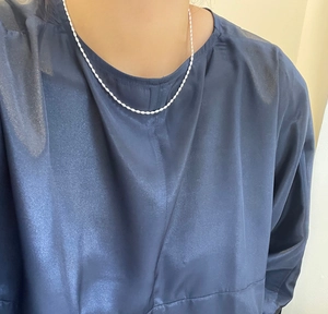 Close-up of S925 sterling silver rice bead necklace on a woman's neck for layered style