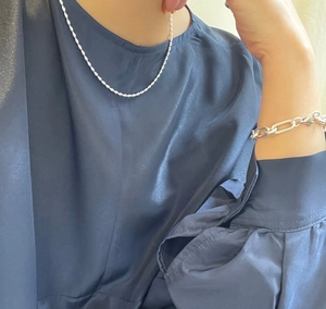 Close-up of S925 sterling silver beaded necklace and paperclip bracelet on silk fabric