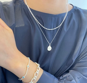 Detail showing layered S925 silver necklaces and bracelet with rice beads and oval pendant