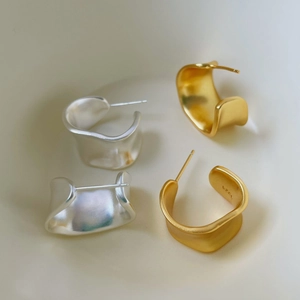 Macro detail of S925 sterling silver matte earrings with wavy half-hoop minimalist design