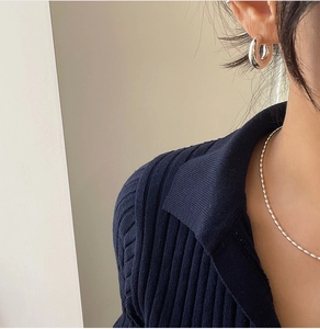 Close-up of polished silver bead necklace and chunky hoop earring on a model