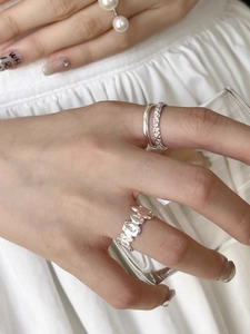 Primo piano di anelli in argento 925 con texture liquida irregolare e fascia minimalista