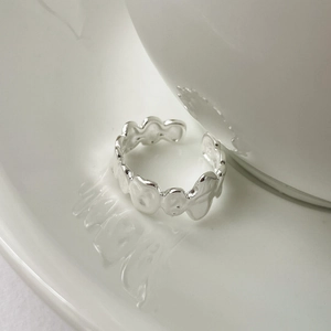 Dettaglio di un anello in argento S925 irregolare su un vassoio in ceramica bianca