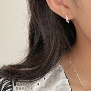 Détail de créoles torsadées en argent portées par un mannequin pour un style minimaliste
