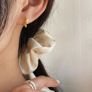 Gros plan de boucles d'oreilles nœuds dorées et bagues argentées sur un mannequin avec chouchou