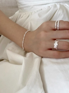 Dettaglio di anelli minimalisti in argento 925 e bracciale a catena indossati da modella