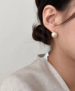 Close-up of minimalist gold rimmed pearl hoop earrings worn for a vintage look