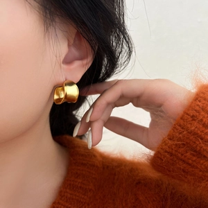 Matte gold S925 sterling silver chunky wave earrings worn by a model in warm lighting